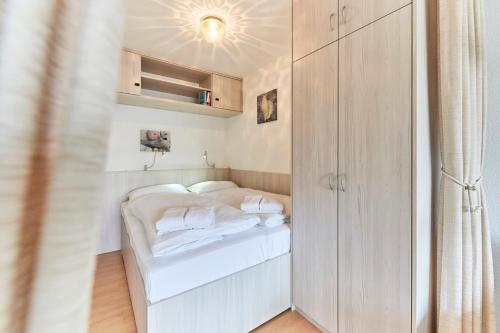 a small white bed in a small room at Terrassenhaus - 9 in Cuxhaven