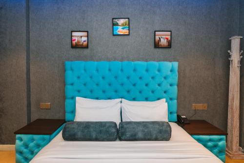 a bed with a blue headboard and three pictures on the wall at Baron Luxury Boutique in Nuwara Eliya