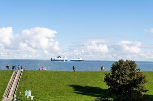 a large ship in the water with people walking on the grass at Nautic - 306 in Cuxhaven