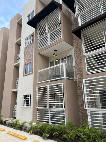 a building with white shutters on its windows at Moderno Apartamento Boca Chica, 5 minutos del Aeropuerto in La Caleta