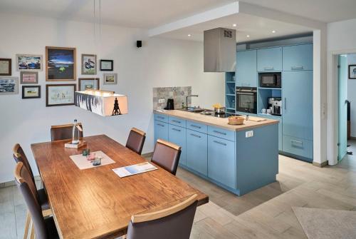 a kitchen with a wooden table and blue cabinets at City Marina - Haus 24A in Cuxhaven