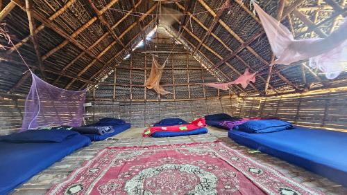 a room with three beds in a straw hut at Time Travellers Hostel in Auroville