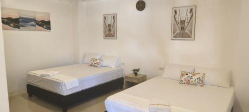 a room with two beds and two pictures on the wall at Evas Guesthouse in General Luna