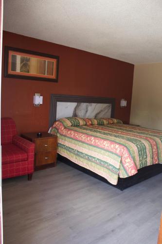 a bedroom with a bed and a red chair at Oak Ridge Inn in Kissimmee