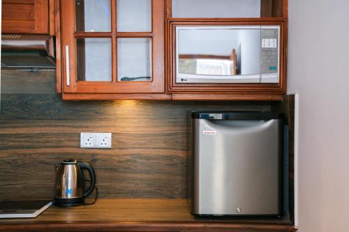 a kitchen with a microwave and a refrigerator at Baron Luxury Boutique in Nuwara Eliya