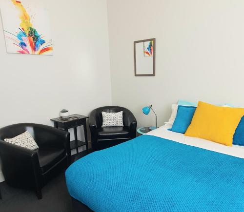 a bedroom with a bed and two black chairs at Work Stay at 123 in Dunedin