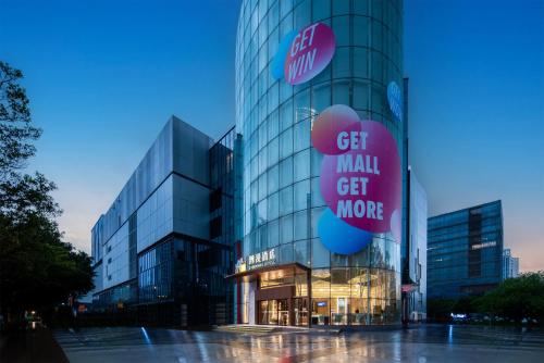 a tall glass building with a sign that says get small get more at Trendy Romantic Hotel International Guangzhou Baoneng Performing Arts Center Science City Metro Station Branch - Free Deliver Service to Guangzhou Baiyun International Airport & Free Deliver Service to Canton Fair Complex During Canton Fair Period in Guangzhou