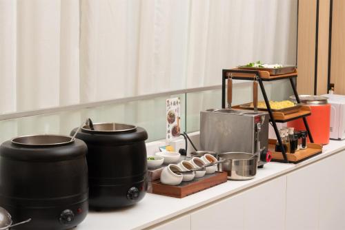 a counter with two large pots and dishes on it at Trendy Romantic Hotel International Guangzhou Baoneng Performing Arts Center Science City Metro Station Branch - Free Deliver Service to Guangzhou Baiyun International Airport & Free Deliver Service to Canton Fair Complex During Canton Fair Period in Guangzhou