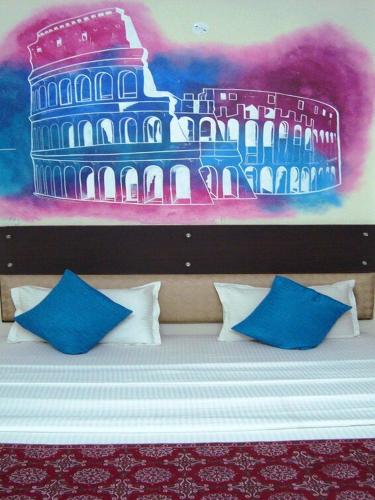 a bed with blue and white pillows and a painting at Gypsy Monkey in Jaipur