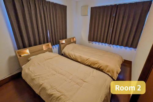 two beds in a small room with a window at Vacation House 1 in Funabashi