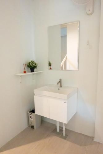 a white bathroom with a sink and a mirror at Kanal Bangkok Service Residence in Ban Khlong Bang Chak