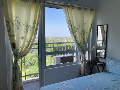 a bedroom with a bed and a large window at SMDC Cool Suite Jane's Condo in Tagaytay
