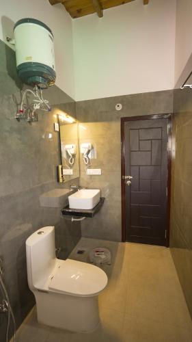 a bathroom with a white toilet and a sink at Kalptaru The Kumaon Retreat in Bhowāli
