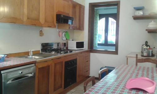 a kitchen with wooden cabinets and a table with a pink hat at Casa Vacanza Dal Contadino CIR O17063 in Alpe Strencia