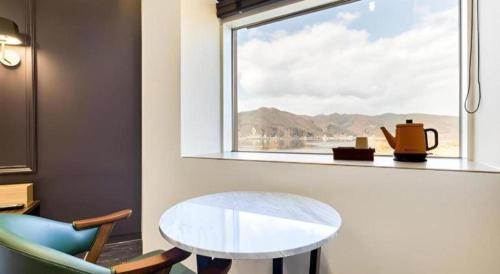 a table and a chair in a room with a window at Plain Hotel in Chuncheon