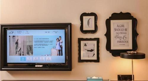 a television on a wall with pictures and a picture frame at Xana Hotelle·Ji'nan Hi-tech Zone Century Avenue Tangye in Jinan