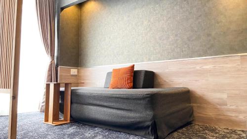 a couch with an orange pillow sitting in a room at SPA HOTEL YUTTARIKAN in Satsumasendai