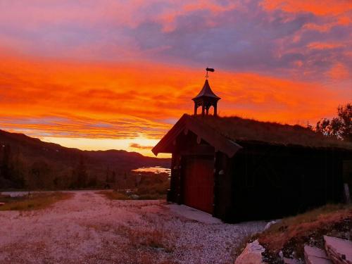 a barn with a cross on top of it at sunset at Log Cabin Near Høgevarde With Mountain Views in Granheim