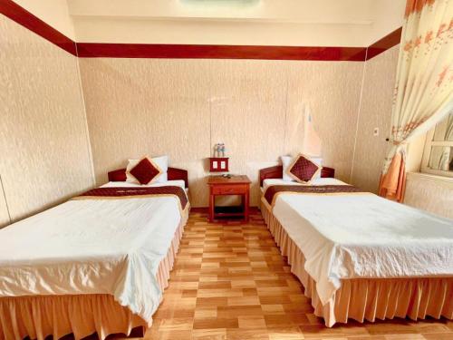 a room with two beds and a table at Bảo Ngọc Hotel Quảng Trị in Lao Bao