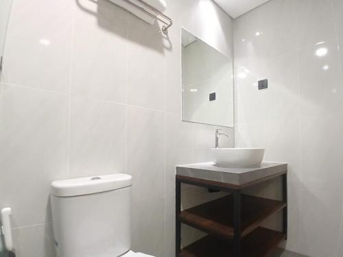 a white bathroom with a toilet and a sink at Vibes Djanti Residence Yogyakarta By Sans Hotel in Demangan