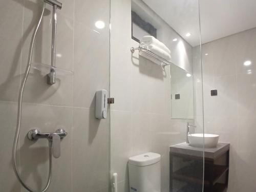 a bathroom with a shower and a toilet and a sink at Vibes Djanti Residence Yogyakarta By Sans Hotel in Demangan