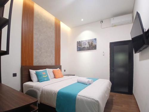 a bedroom with two beds and a flat screen tv at Vibes Djanti Residence Yogyakarta By Sans Hotel in Demangan