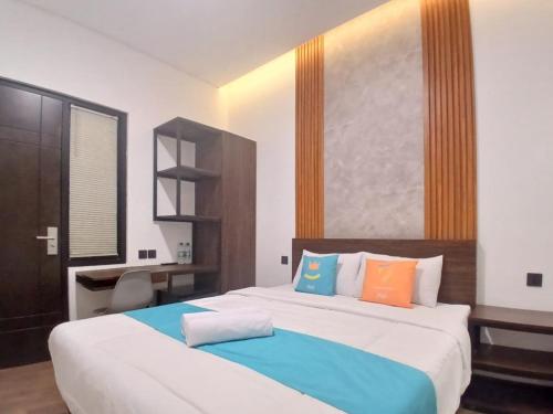 a bedroom with two beds and a desk in it at Vibes Djanti Residence Yogyakarta By Sans Hotel in Demangan