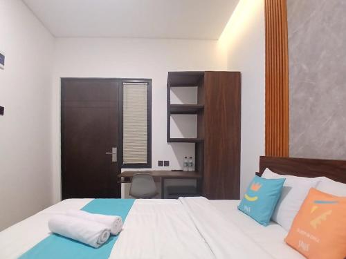a bedroom with a bed with a desk in it at Vibes Djanti Residence Yogyakarta By Sans Hotel in Demangan