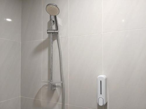 a shower with a shower head in a bathroom at Vibes Djanti Residence Yogyakarta By Sans Hotel in Demangan
