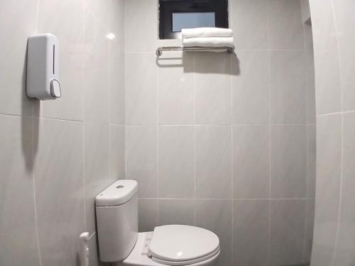a white bathroom with a toilet and a window at Vibes Djanti Residence Yogyakarta By Sans Hotel in Demangan