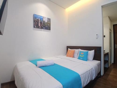 two beds in a white room with blue and orange pillows at Vibes Djanti Residence Yogyakarta By Sans Hotel in Demangan