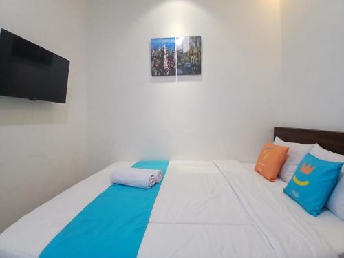 a bedroom with a white bed with colorful pillows at Vibes Djanti Residence Yogyakarta By Sans Hotel in Demangan