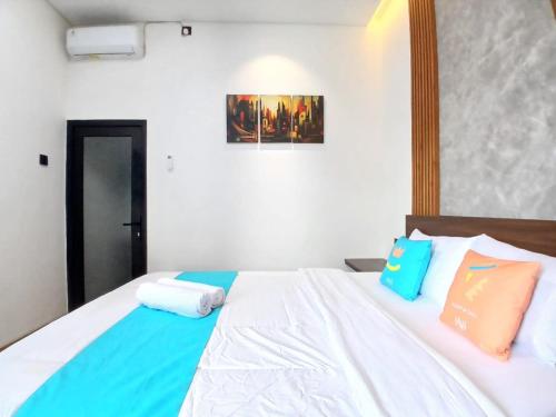a bedroom with a white bed with blue and orange pillows at Vibes Djanti Residence Yogyakarta By Sans Hotel in Demangan
