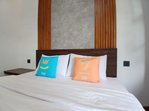 a bed with three pillows on top of it at Vibes Djanti Residence Yogyakarta By Sans Hotel in Demangan