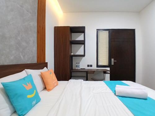 a bed with two pillows and a desk in a room at Vibes Djanti Residence Yogyakarta By Sans Hotel in Demangan