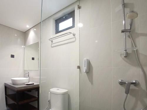 a bathroom with a shower and a toilet and a sink at Vibes Djanti Residence Yogyakarta By Sans Hotel in Demangan