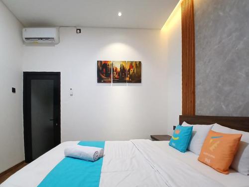 a bedroom with a bed with blue and orange pillows at Vibes Djanti Residence Yogyakarta By Sans Hotel in Demangan