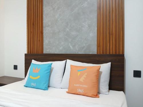 a bed with three pillows on top of it at Vibes Djanti Residence Yogyakarta By Sans Hotel in Demangan