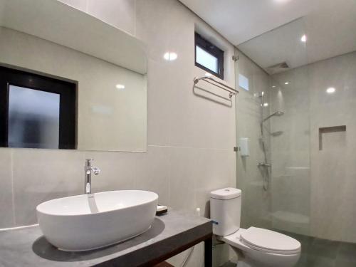a white bathroom with a sink and a toilet at Vibes Djanti Residence Yogyakarta By Sans Hotel in Demangan