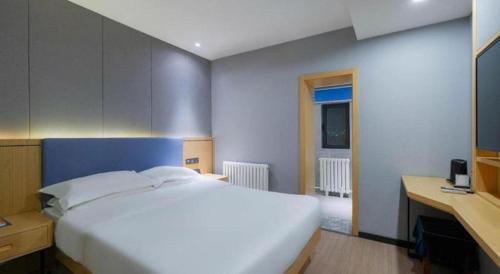 a bedroom with a large white bed and a desk at Green Tree Inn Urumqi San'gong Metro Station Exit in Ürümqi