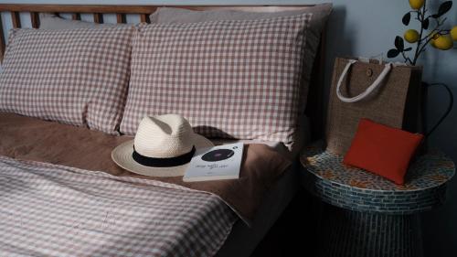 a hat and a book on a bed with pillows at MayHome Binh Dinh in An Hòa