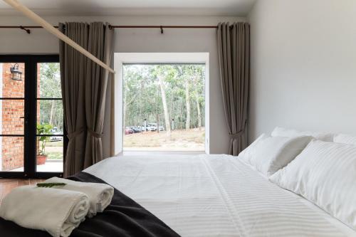 a bedroom with a large bed and a large window at The Rubber Escape, Melaka in Melaka