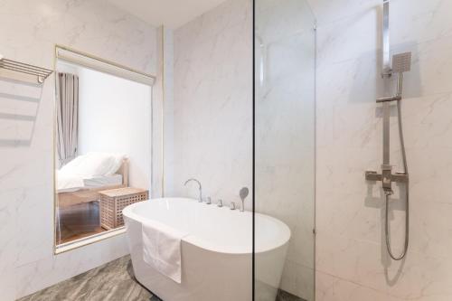 a white bathroom with a tub and a shower at The Rubber Escape, Melaka in Melaka