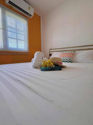 a white bed with a book and flowers on it at Karoon Sea View Lodge in Hua Hin