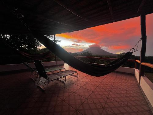 a hammock on a balcony with a view of a mountain at Finca Aisa -Boutique bungalows in Ometepe island in Santa Cruz
