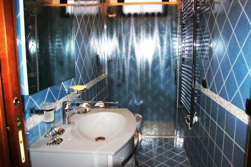 La salle de bains est pourvue de carrelage bleu, d'un lavabo et de toilettes. dans l'établissement B&B La Piccola Oasi, à Lazzaro