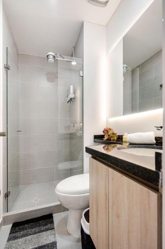 a white bathroom with a toilet and a shower at Citalofty in Bogotá