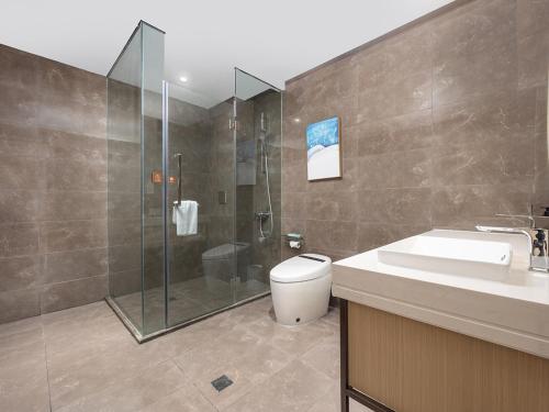 a bathroom with a shower and a toilet and a sink at Kyriad Hotel in Tianjin