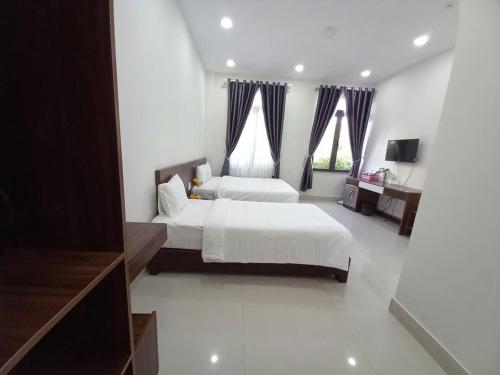 a large white bedroom with two beds and a television at Đà Lạt Cao Nguyên Hotel in Da Lat