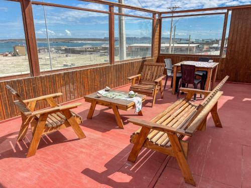a deck with wooden benches and tables and windows at Hostal restaurante Hidalgo in Punta de Choros